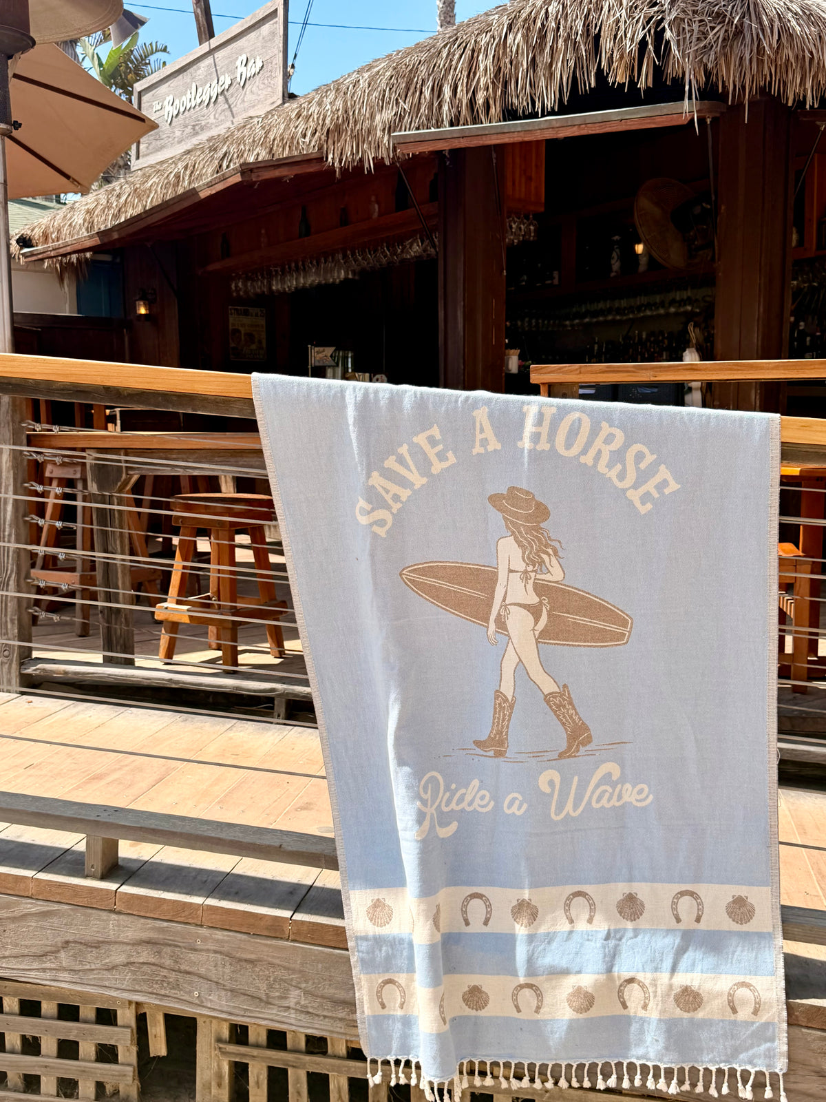 Save a Horse Ride a Wave Turkish cotton beach towel hanging at a seaside restaurant