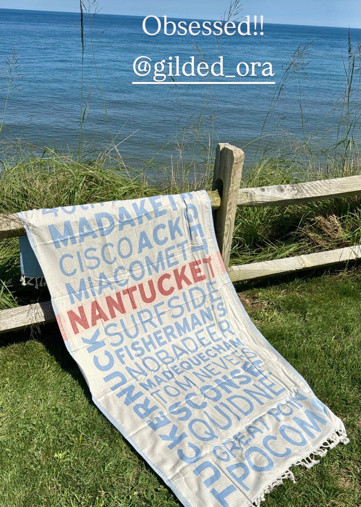 ACK Beaches Turkish cotton beach towel draped over a fence overlooking the water on Nantucket